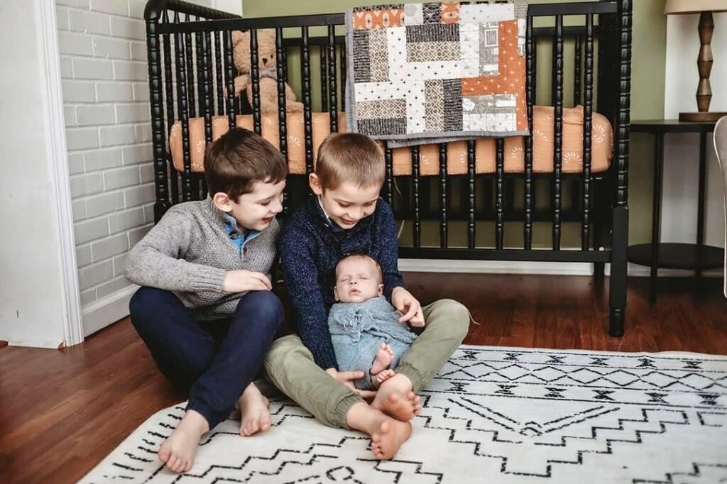 youngest grandbaby with his big brothers and nursery quilt